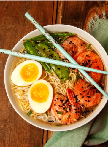 A bowl of spicy shrimp ramen with chop sticks laying on top. 